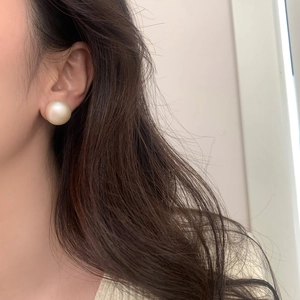 Elegant large matte pearl stud earrings worn by a model in a natural side profile view