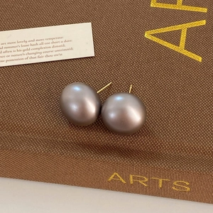 Macro shot of gray pearl studs with gold pins on an elegant fabric gift box background