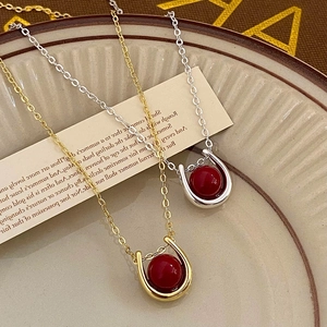 Detail of horseshoe pendants with red beads in gold and silver finish on ceramic plate