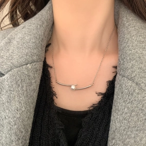 Élégant collier argenté avec un pendentif métallique unique et une perle lustrée