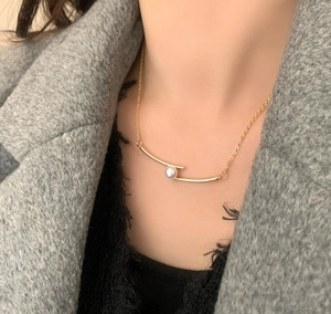 Gros plan détaillé d'un collier doré avec pendentif en perle porté par un mannequin