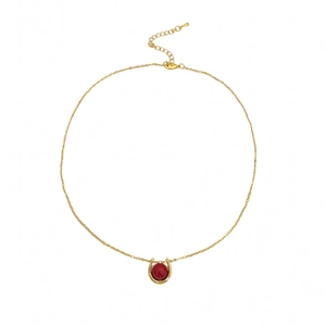Minimalist gold necklace with a red bead in a horseshoe pendant on a white background