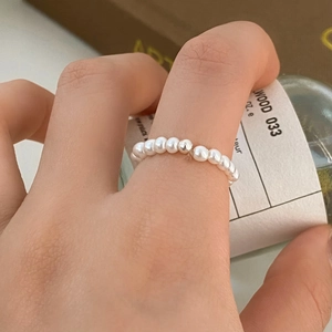 Close-up of minimalist freshwater pearl ring with a single silver bead on model hand
