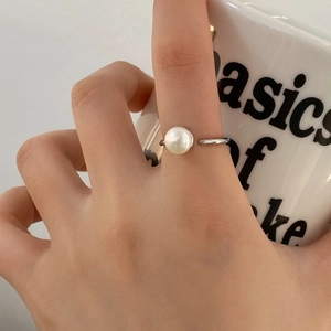 Close-up of a minimalist adjustable silver ring with a round white freshwater pearl