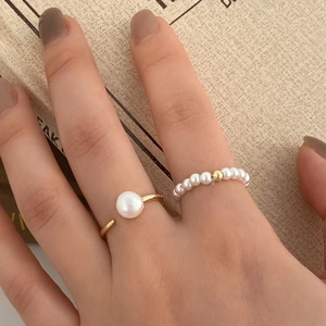 Detail of freshwater pearl gold open ring and elastic beaded ring for layered wear