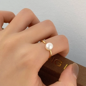 Close-up of minimalist gold ring with white freshwater pearl worn on the finger