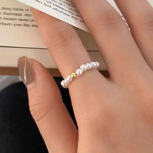 Detail of freshwater pearl elastic ring with a gold bead accent worn on finger