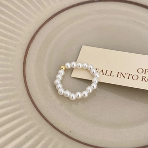 Close-up of minimalist freshwater pearl beaded ring with a single gold bead on ceramic
