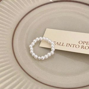 Detailed macro view of a minimalist freshwater pearl beaded ring on a cream ceramic tray