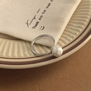 Close-up of elegant silver pearl ring on ceramic tray with minimalist aesthetic