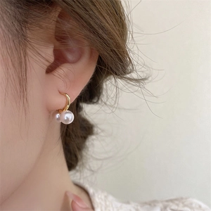 Dettaglio di orecchini vintage in oro con eleganti doppie perle a goccia pendenti