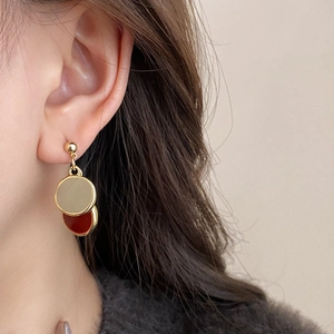 Gros plan de boucles d'oreilles doubles disques élégantes or champagne et rouge foncé