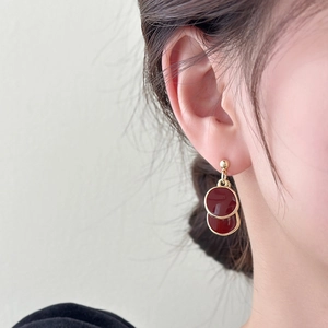 Détail de boucles d'oreilles vintage avec émail bordeaux et finition dorée élégante