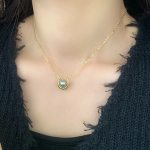 Elegant French gold chain necklace with grey pearl in horseshoe pendant on black garment