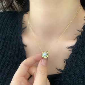 French style minimalist gold necklace with horseshoe pendant and white pearl on black sweater