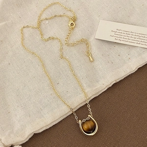 Detailed shot of golden horseshoe necklace with tiger eye stone on rustic linen