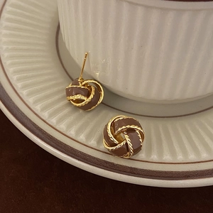 Vintage gold twist knot stud earrings with brown oil drop finish on ceramic dish