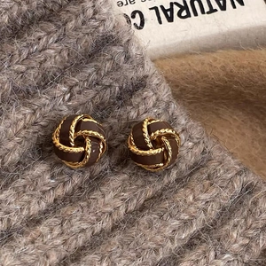 Detailed shot of coffee brown enamel twist earrings on a gray knitted background