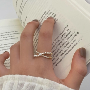 Vue macro d'une bague croisée dorée avec perles et pierres sur fond de livre
