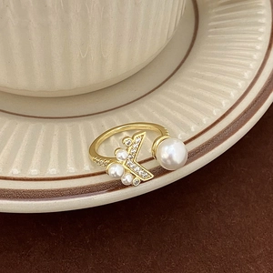 Détail macro d'une bague queue de poisson dorée avec perles blanches et zircons