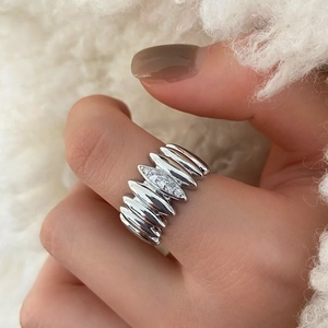 Macro detail of silver wide ring with ribbed texture and three cubic zirconia stones