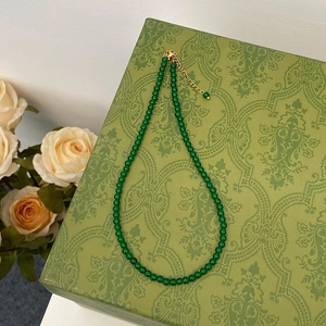 Close-up of green chalcedony beaded necklace with golden clasp on vintage floral box