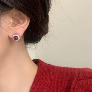 Élégantes boucles d'oreilles halo en rubis rouge et cristaux portées par un mannequin
