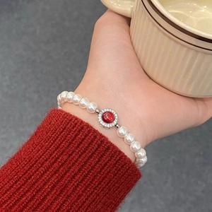 Bracelet élégant en perles et pierre rouge porté dans une ambiance de maison douce