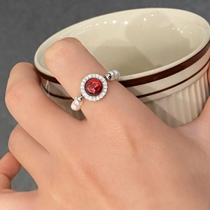 Gros plan d'une bague vintage avec pierre rouge et anneau en perles porté à la main