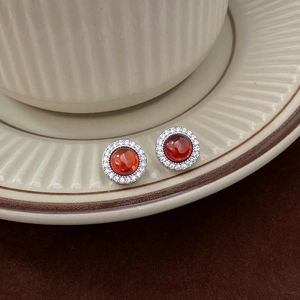 Vue macro de boucles d'oreilles rétro en argent avec pierre rouge et halo de zircons