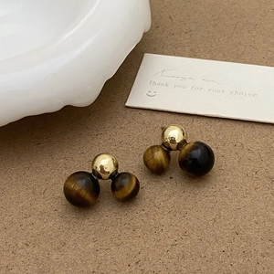 Gros plan de boucles d'oreilles en œil de tigre avec détails dorés sur papier texturé