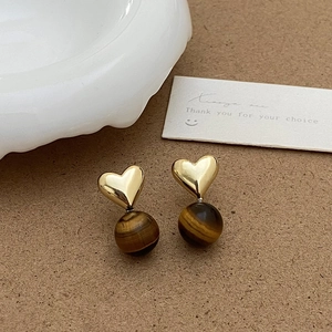 Gros plan de boucles d'oreilles cœur vintage avec métal doré et perles d'œil de tigre