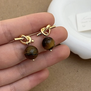 Gros plan de boucles d'oreilles œil de tigre vintage avec clous dorés torsadés élégants
