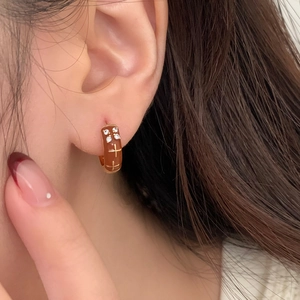 Brown resin hoop earrings with small white zircons and golden cross design on model