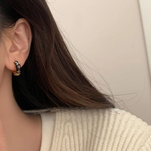 Detail of black enamel hoop earrings with gold cross pattern and zircon inlay on model
