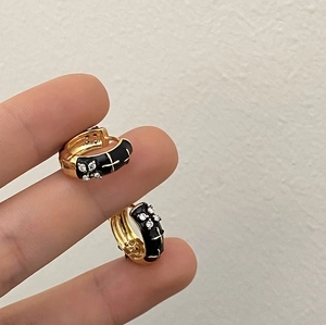 Close-up of gold hoop earrings with black enamel and butterfly zircon detailing