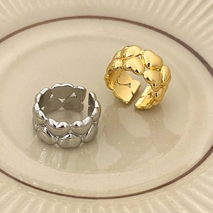 Dettaglio di anelli regolabili a doppio cuore in oro e argento su un vassoio ceramico
