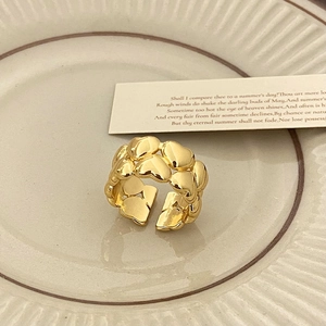Dettaglio anello vintage dorato a doppia fila di cuori su un vassoio color crema