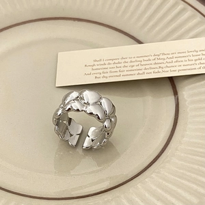 Dettaglio dell'anello aperto argento con rilievo a cuore su un piatto vintage