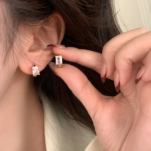 Orecchini in oro con zircone quadrato, indossati da una modella per un look raffinato