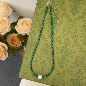 Détail d'un collier de perles vert malachite avec perle centrale sur motif floral