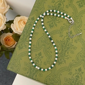 Détail du collier de perles et turquoise avec fermoir argent sur fond floral vintage