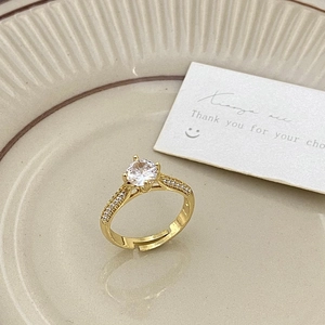 Detailed close-up of a gold ring with a sparkling zircon solitaire in a ceramic dish