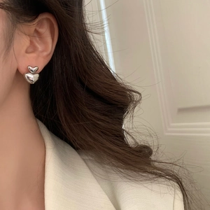 Close-up of double heart silver earrings worn by model for a stylish fashion look