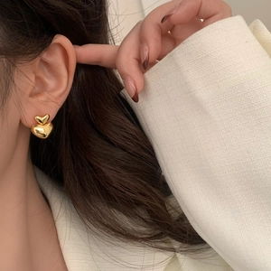 Close-up of golden double heart earrings on model showing shiny metallic finish