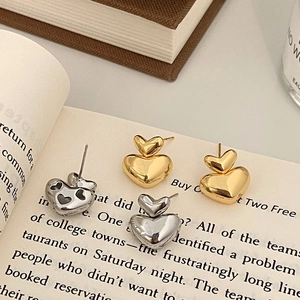 Double heart stud earrings in gold and silver finish placed on a book page