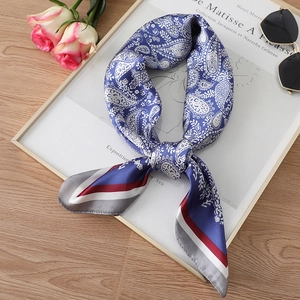 Close-up of navy paisley silk scarf with striped borders on a wooden table display