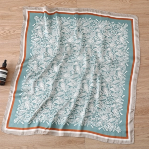 Detail shot of paisley pattern silk scarf with teal background on wooden floor