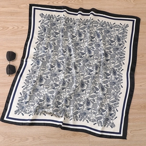 Detail of paisley print silk scarf with black border on a wooden texture background