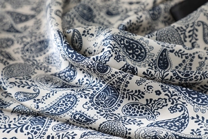 Close-up of navy blue paisley print on silky cream fabric showing texture and drape